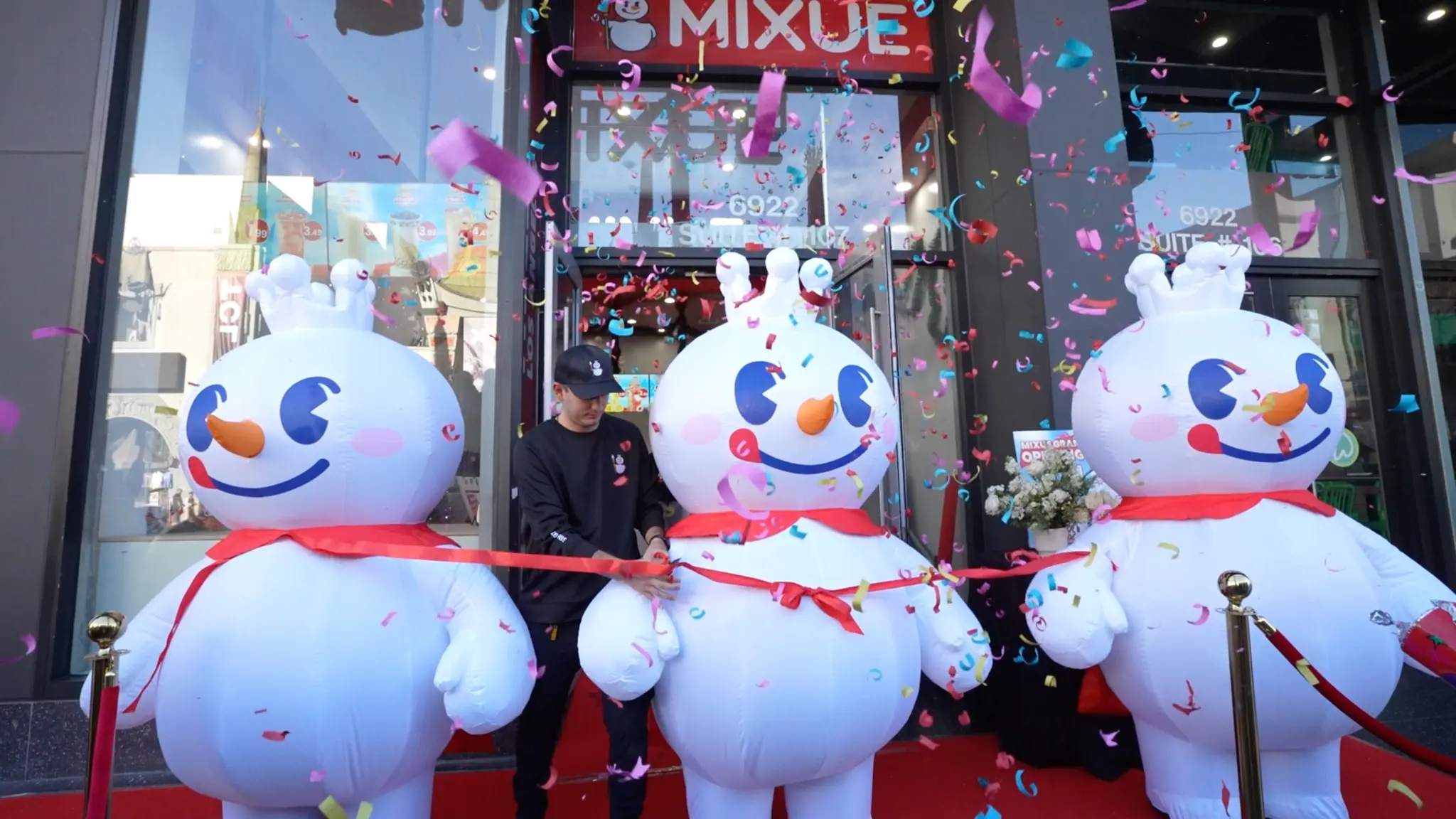 Mascote gigante de boneco de neve MIXUE em rua de inverno com multidão de pessoas tirando fotos
